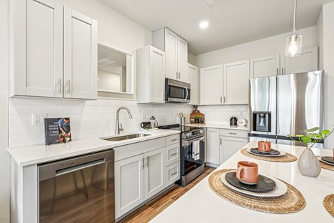 A modern kitchen with white cabinets and stainless steel appliances.