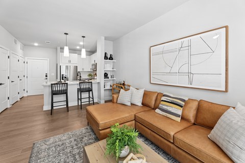 A living room with a brown leather couch and a large abstract painting on the wall.