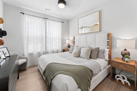 A bedroom with a large bed and a wooden nightstand.