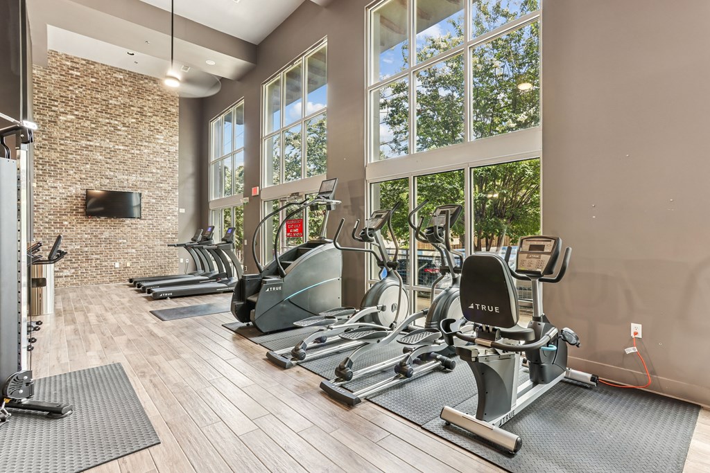A gym with a brick wall and a row of exercise bikes.