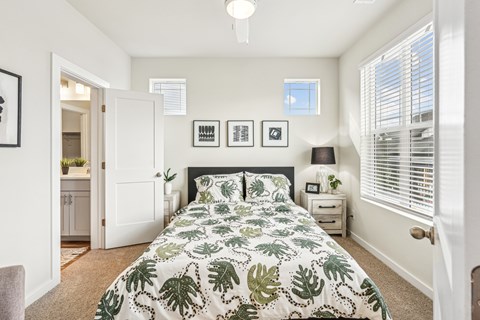 A bedroom with a large bed and a green leaf patterned comforter.