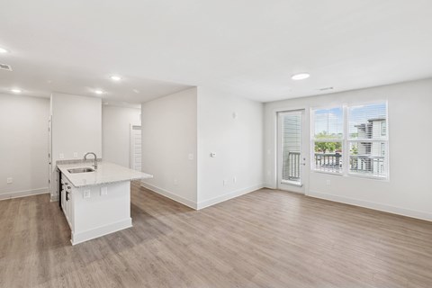 A white kitchen with a sink and a window overlooking a cityscape.