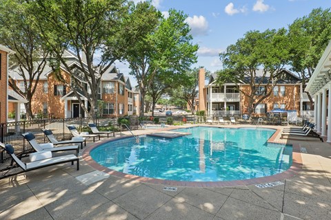 A swimming pool surrounded by trees and chairs in a residential area.
