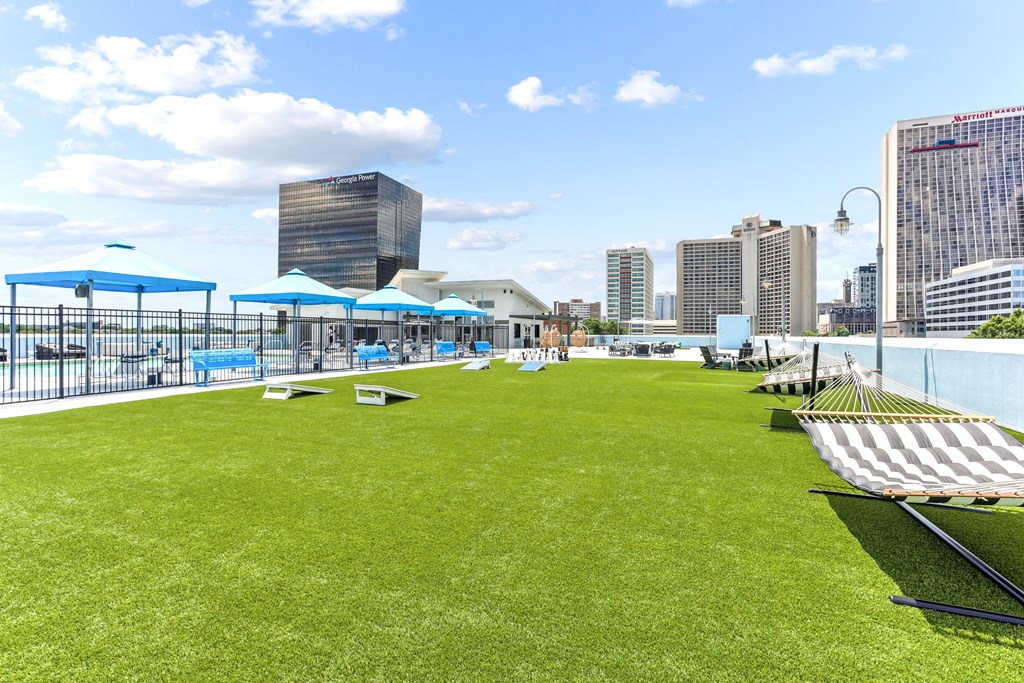 A large grassy area with a fence and a few umbrellas.
