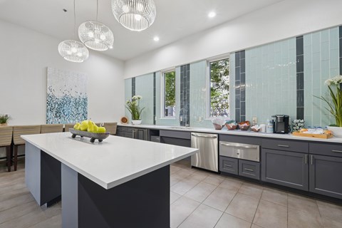 A modern kitchen with a large island and pendant lights.