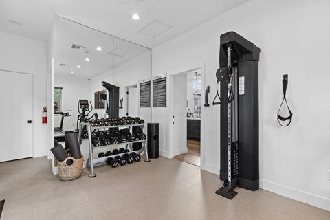A gym room with a weight rack and a mirror.