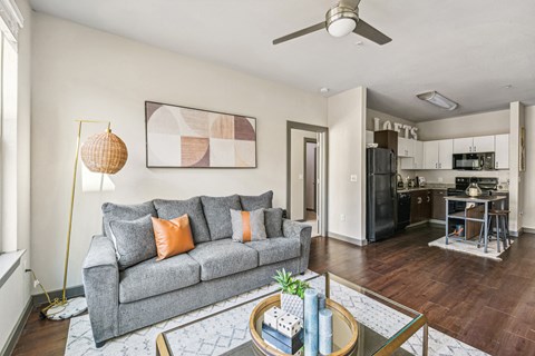 A living room with a grey couch and a painting on the wall.
