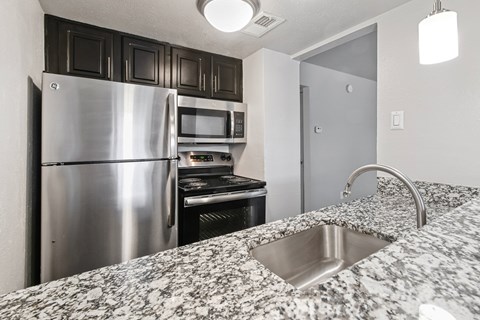 A kitchen with a stainless steel refrigerator and microwave.