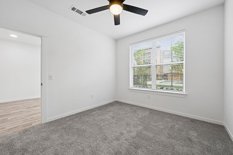 A room with a ceiling fan and a window with blinds.