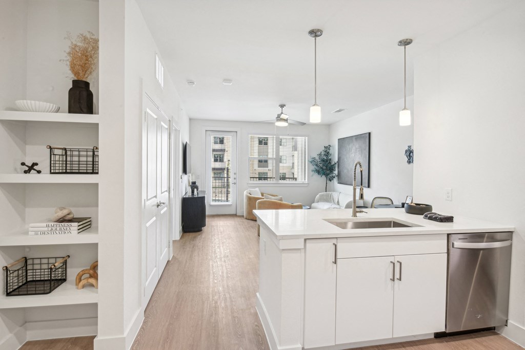 A modern kitchen with white cabinets and a wooden floor.
