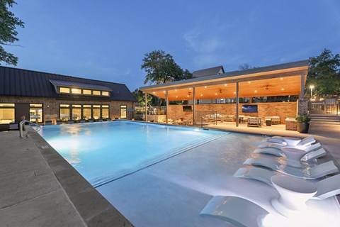 A large outdoor swimming pool with loungers and a building in the background.