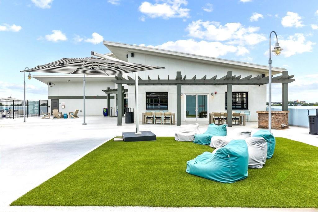 A white building with a black roof and a white awning with a green lawn in front.