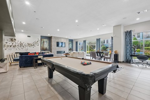 A pool table is in the middle of a room with a blue sofa and a painting on the wall.