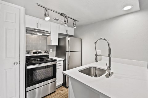 A modern kitchen with white cabinets and stainless steel appliances.