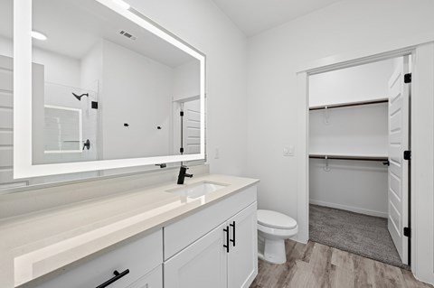 A white bathroom with a sink, mirror, and toilet.