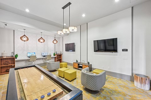 A shiny pool table is in the middle of a room with a yellow chair and a television.