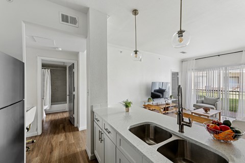 A kitchen with a white counter top and a bowl of fruit on it.