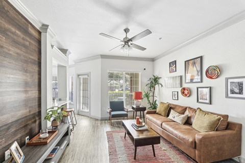 A living room with a brown couch and a ceiling fan.