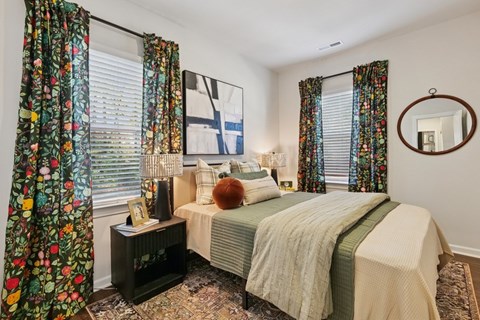 A bedroom with a bed, a nightstand, and a mirror.