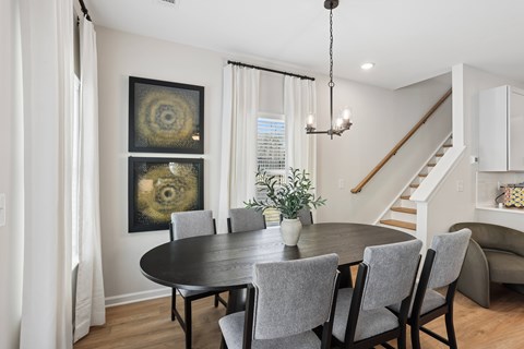 A dining room with a black table and chairs.