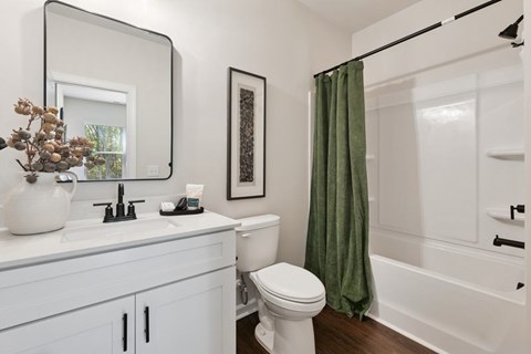 A white toilet sits in a bathroom next to a white sink and a white bathtub.