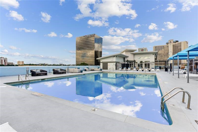 A swimming pool with a blue sky and clouds reflected in the water.