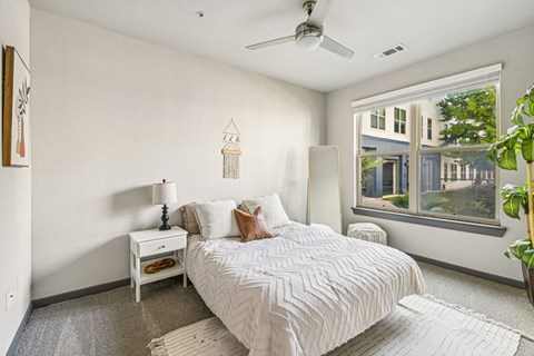 A bedroom with a large bed and a window overlooking a building.