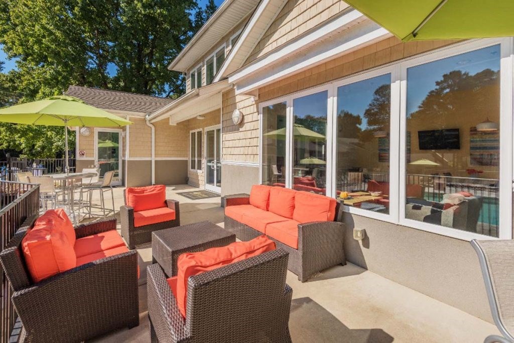 a patio with orange and black furniture and a pool in the background