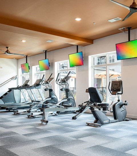 A gym with a row of exercise bikes and a fan.