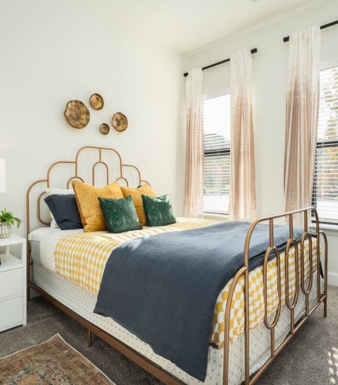 A bed with a blue blanket and yellow pillows is in the image.