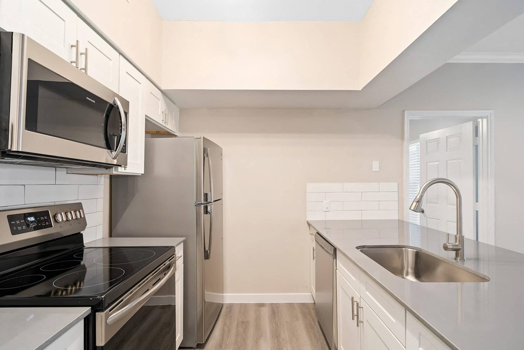 a modern kitchen with stainless steel appliances and white cabinets