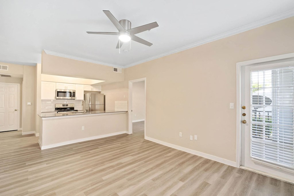 a living room with a kitchen and a ceiling fan