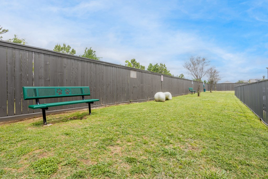 a yard with a green bench and a fence and two sheep