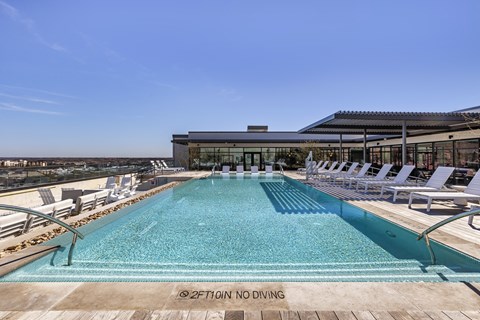 a swimming pool with white lounge chairs and a building in the background