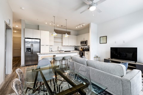A modern living room with a glass coffee table and a grey sofa.