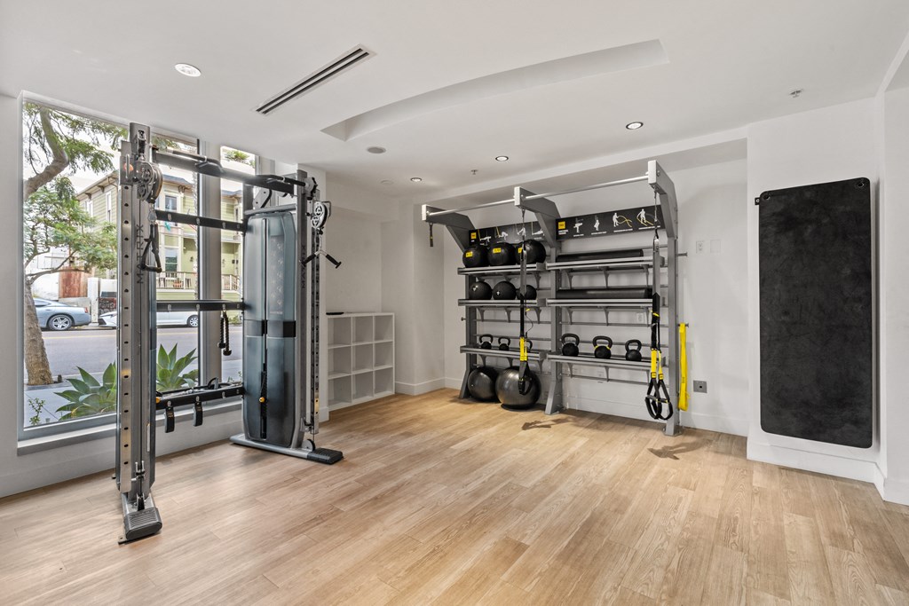 a gym with weights and a large window and a wooden floor