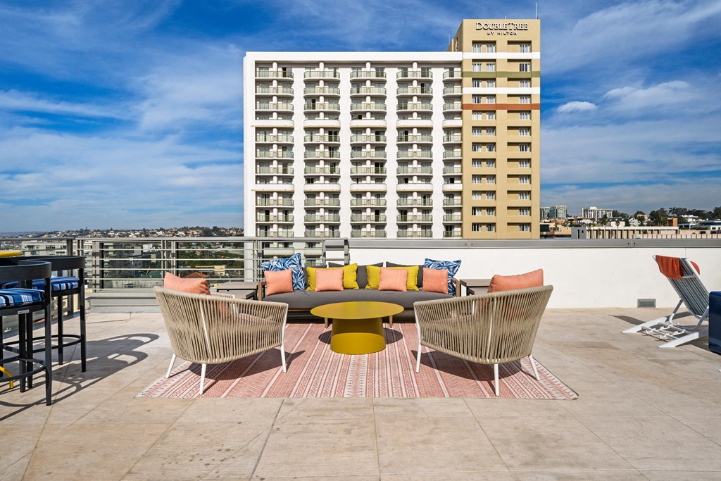 a rooftop patio with a couch and chairs and a building in the background
