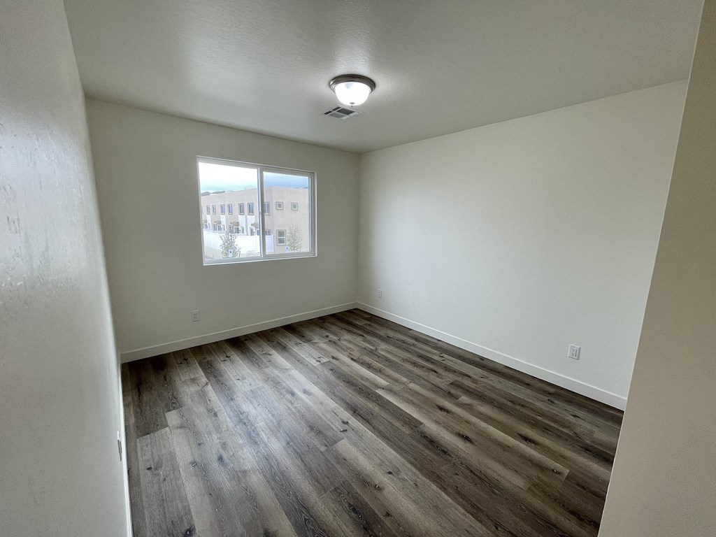 an empty living room with wood flooring and a window