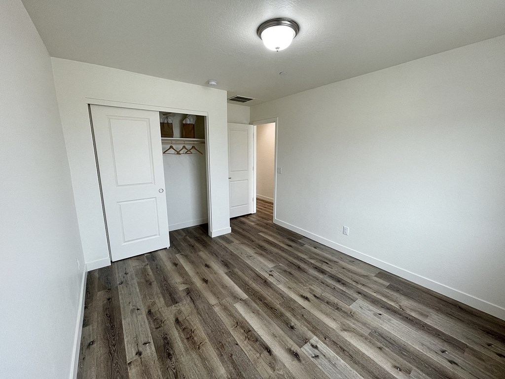 a long hallway with white walls and wood flooring