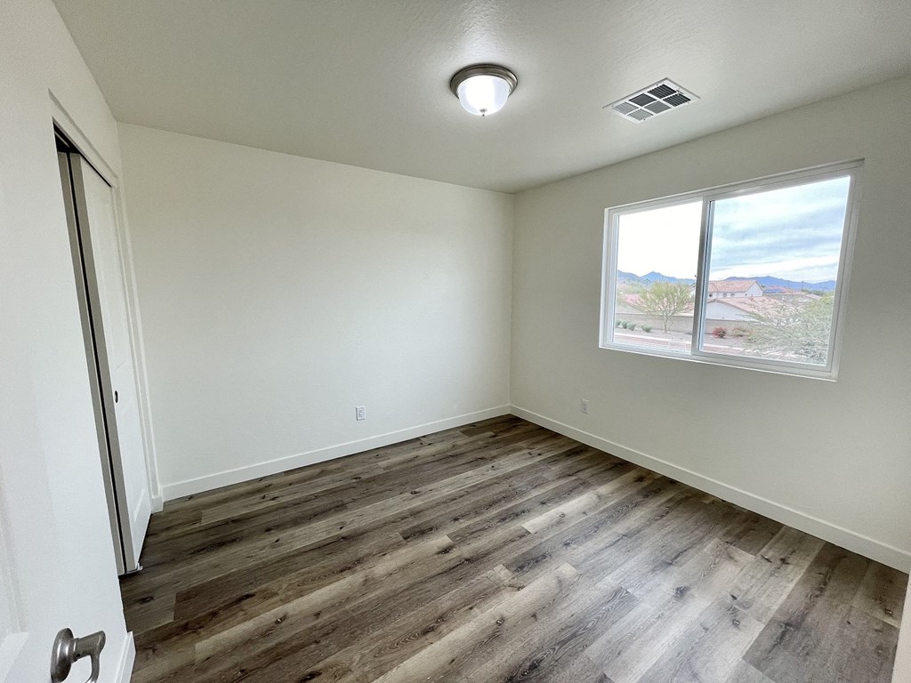 an empty living room with wood flooring and a window
