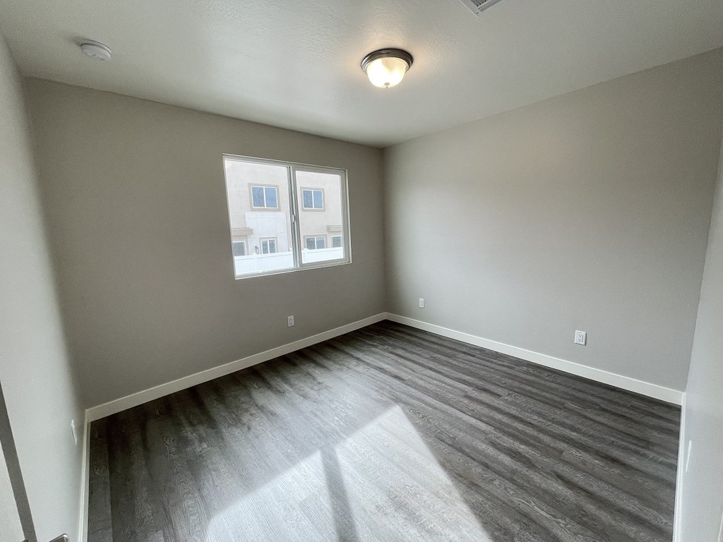 an empty living room with gray walls and a window