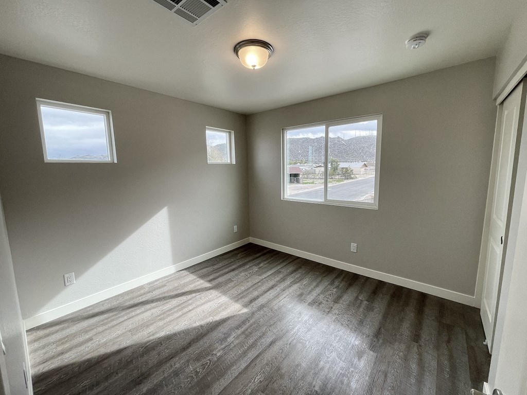 an empty living room with wood floors and a window