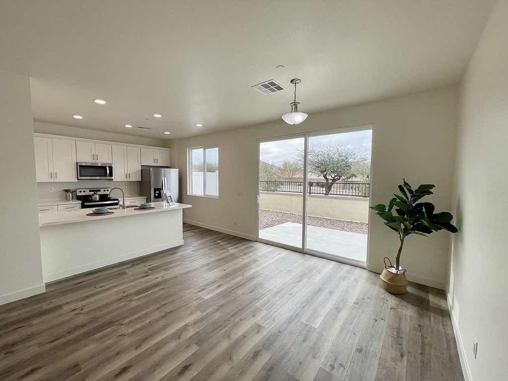 an empty living room with a kitchen and a sliding glass door