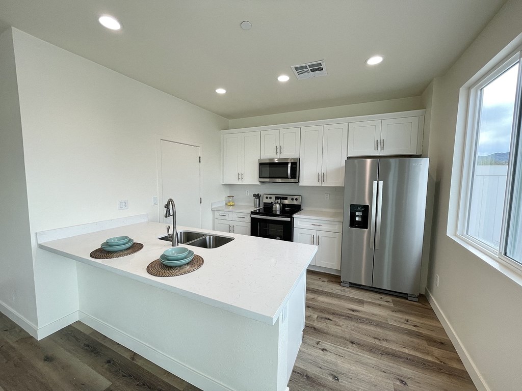 a kitchen with a large island and a stainless steel refrigerator