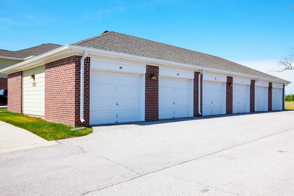 a garage with three white garage doors on the side of a house