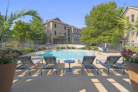 A pool area with chairs and a building in the background.