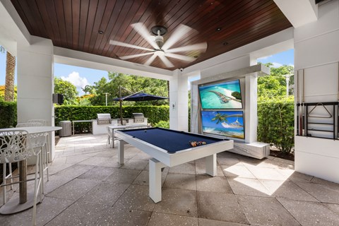 a patio with a pool table and a ceiling fan