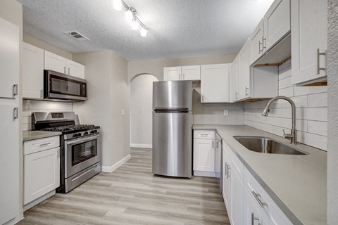 a kitchen with white cabinets and stainless steel appliances