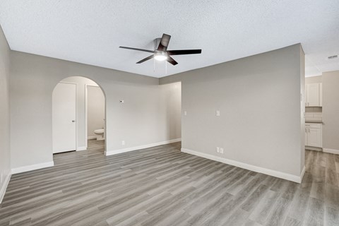 an empty living room with a ceiling fan