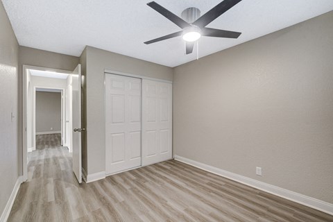 an empty bedroom with a ceiling fan